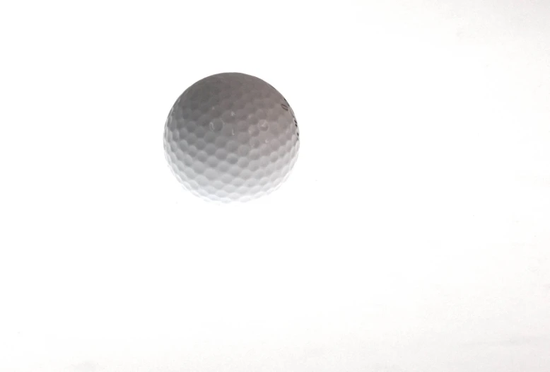 a golf ball flying in the air near a white background