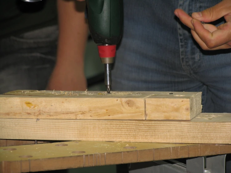 a man is using a drill to cut a piece of wood