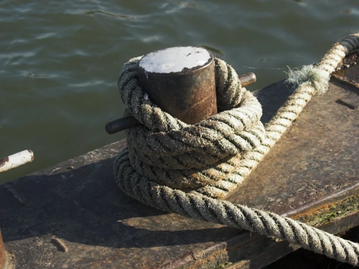 roped ropes and wooden post sit atop of the end of a dock