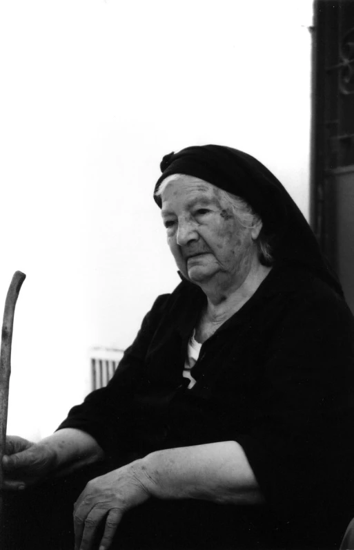 a black and white image of an old woman wearing a robe