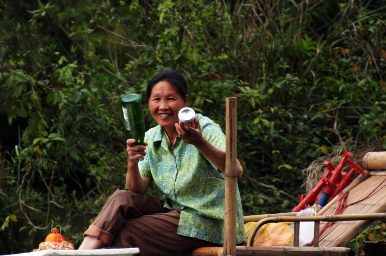 a woman is holding two bottles while sitting on a chair