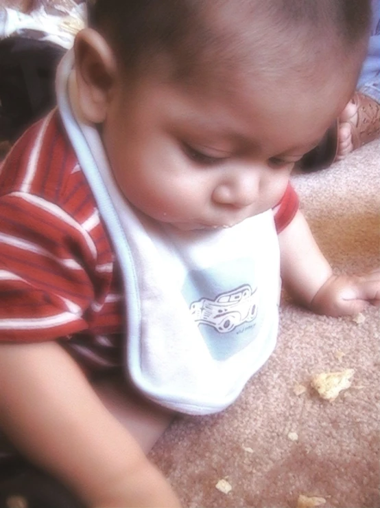 a baby holding up a bib while wearing a bib