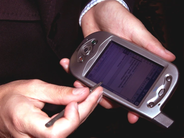 two hands holding a mobile phone displaying a program