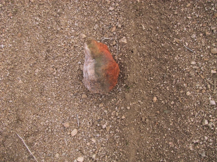 the orange colored rock is in the middle of the gravel