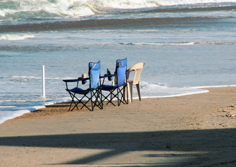 four chairs are sitting on the beach and next to an empty pole