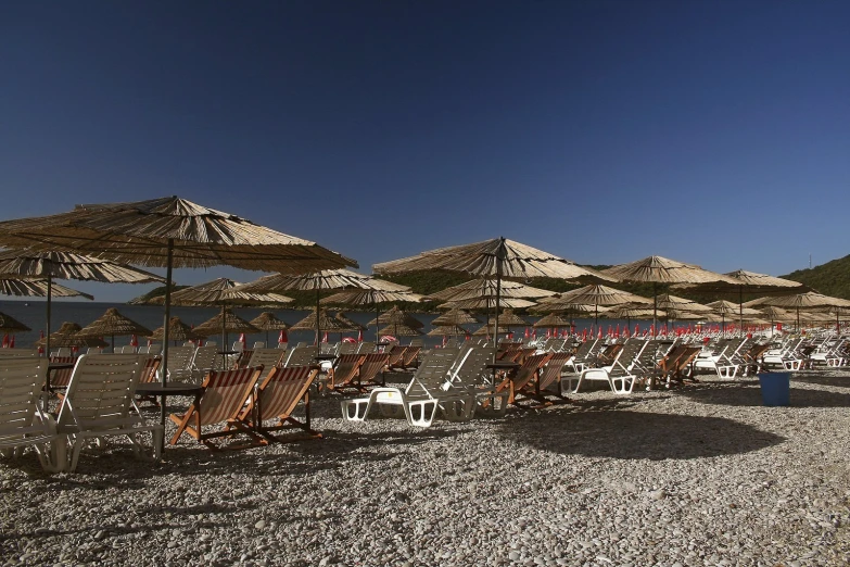 several lawn chairs and umbrellas on a beach