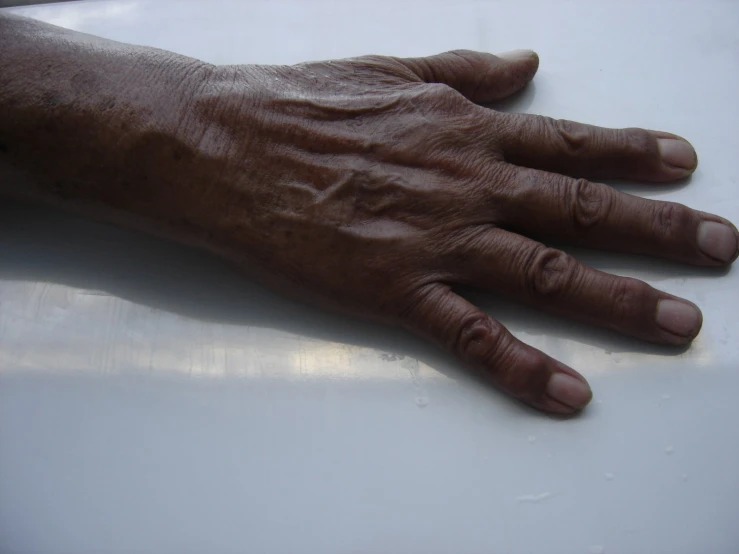 a person's hand with very large nails on top of a white surface