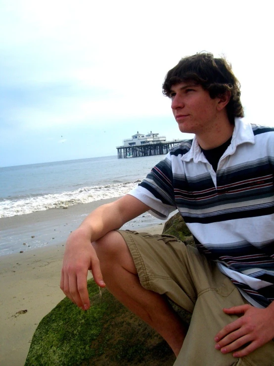 a man sitting on top of green grass on top of a beach