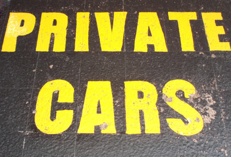 yellow and black painted words on the side of a parking sign