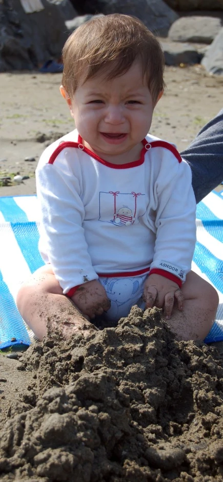 a small child plays with the dirt on a towel