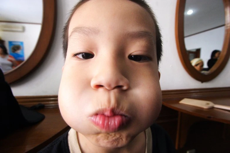 an adorable little asian boy making funny faces