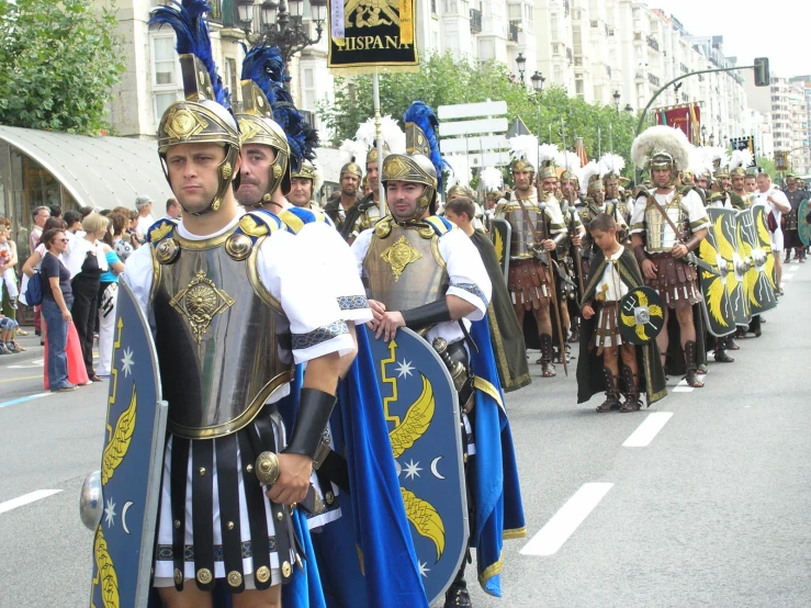 two men in costumes and helmets are standing with other people on the road