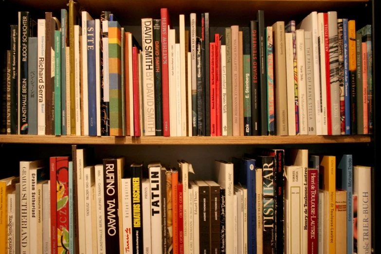 books are piled on a wooden shelf beside each other