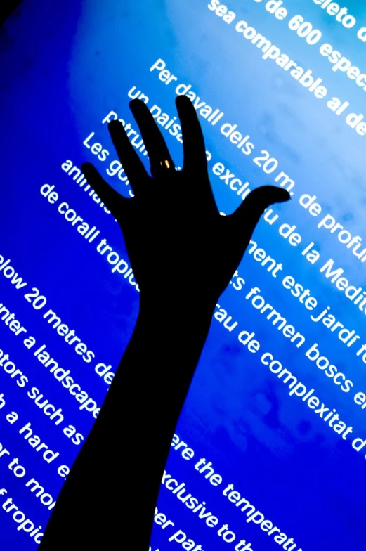 a hand rising from a computer display with blue background