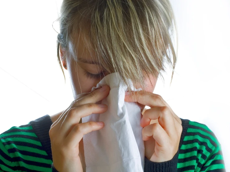 a young woman is holding her nose to a napkin