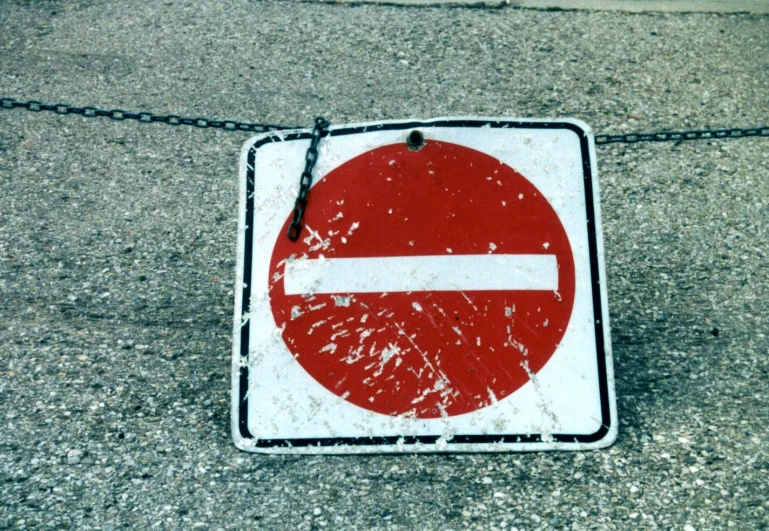 a red and white no parking sign sitting on a sidewalk