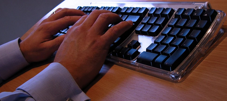 a person wearing a suit and tie working on a computer keyboard