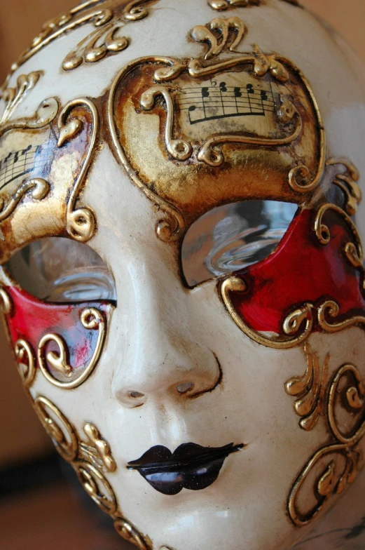 the mask is painted red and gold with music on it