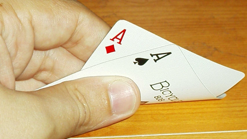 hand with two cards held up by thumb