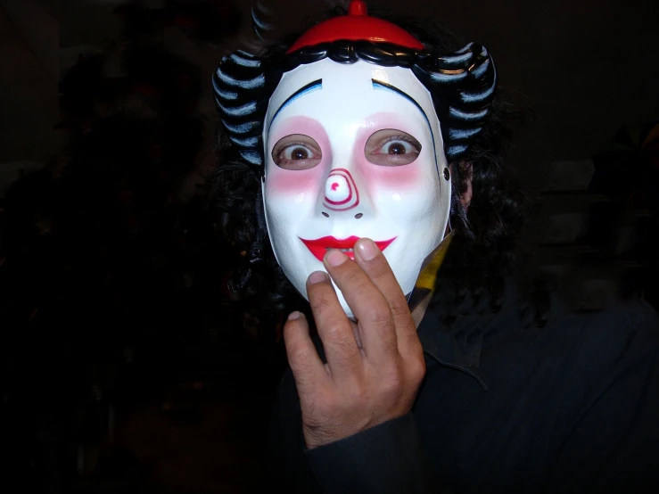 a man in an evil mask holding a cigarette and smoking