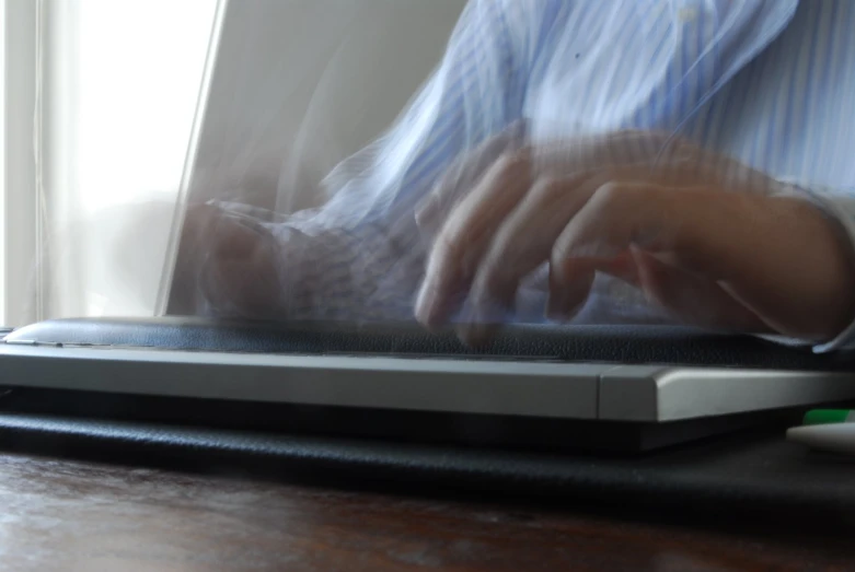 a blurry po shows a man's hand on the keyboard