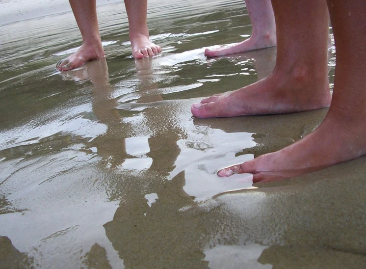 three feet are shown on the sand in front of water