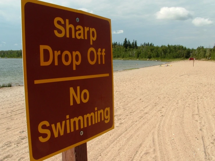 a beach with a sign on it stating to chop drop off, no swimming