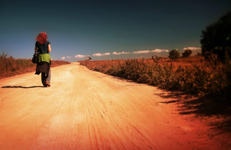 the girl is walking on the road with the green top on