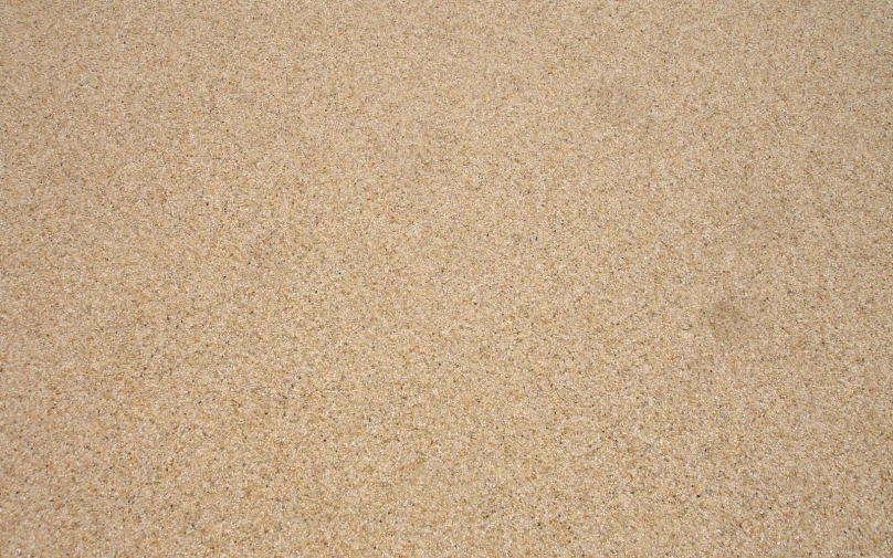 a close up of a sand background with some black dots