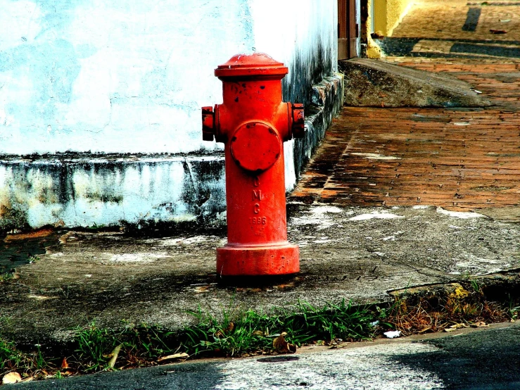 a fire hydrant on a city street near a wall