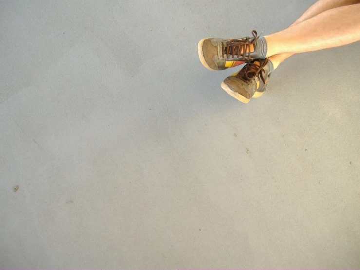 a woman is sitting on a floor wearing a pair of sneakers