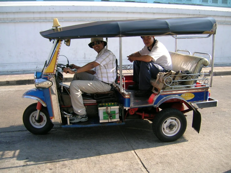 two men are riding an electric rickshaw