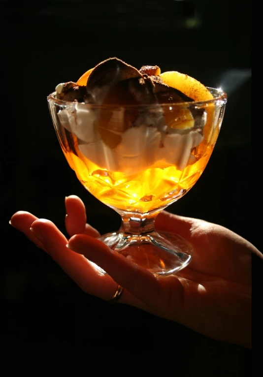 a person holds an orange in a wine glass