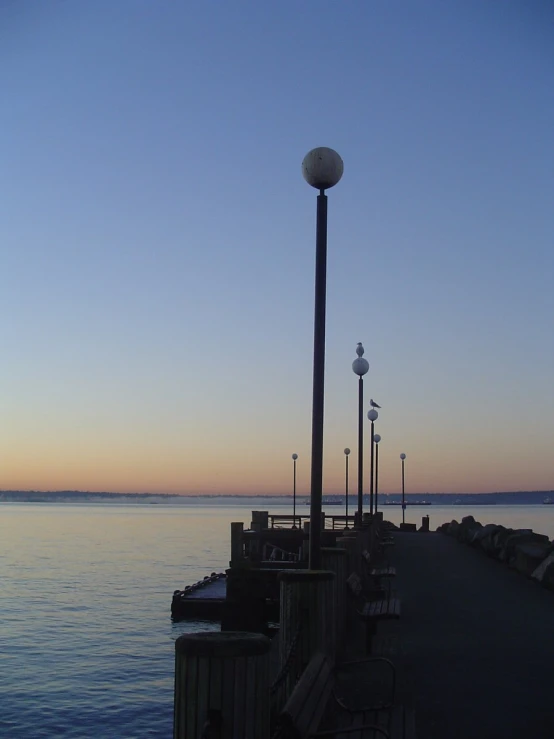 the side of a long pier is lined with benches