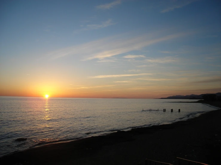 sun is setting on the horizon at an empty beach