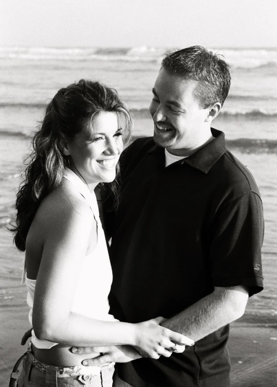 man and woman standing together while holding each other close by the beach