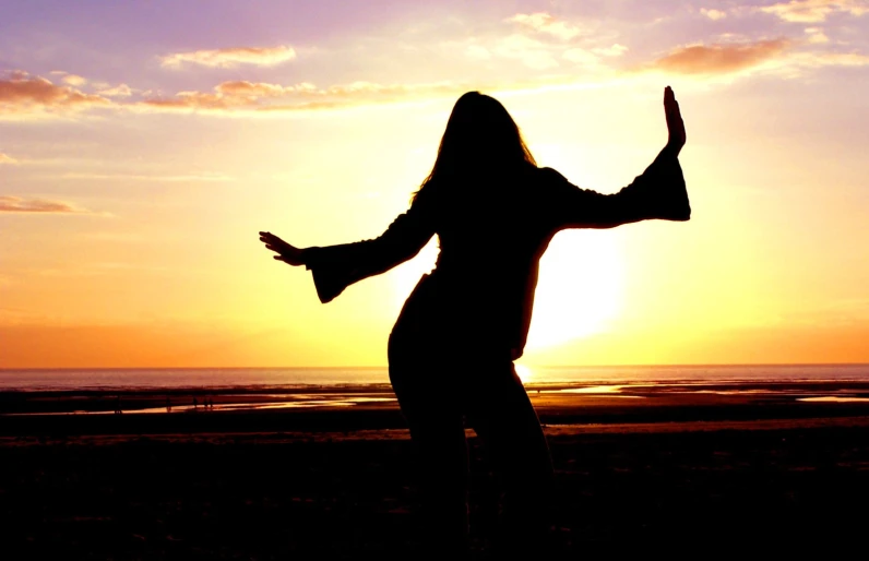 a woman is silhouetted by the sun and dancing