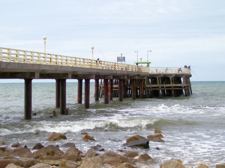 some rocks and a wooden pier on the ocean