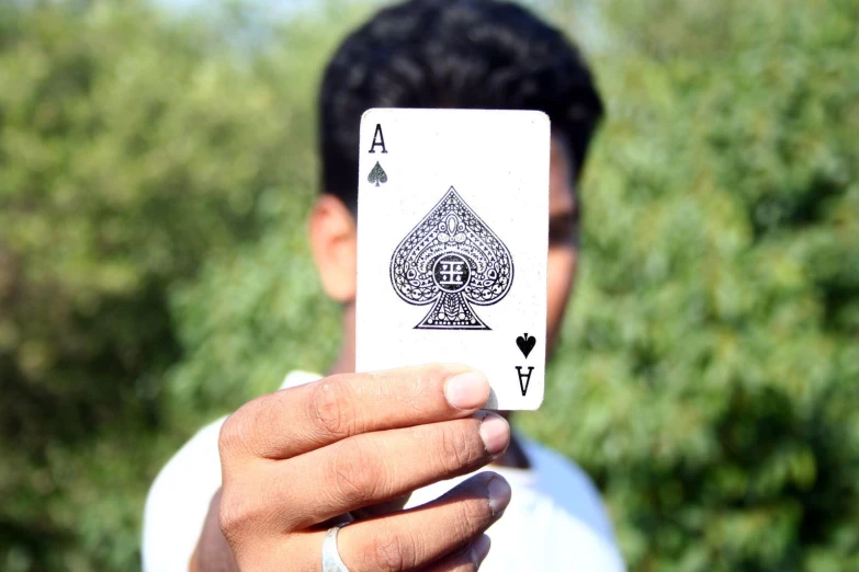 a man holding up a card with a stylized ace on the inside