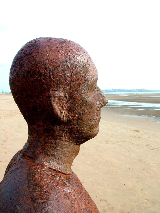 an old statue looks out to the beach