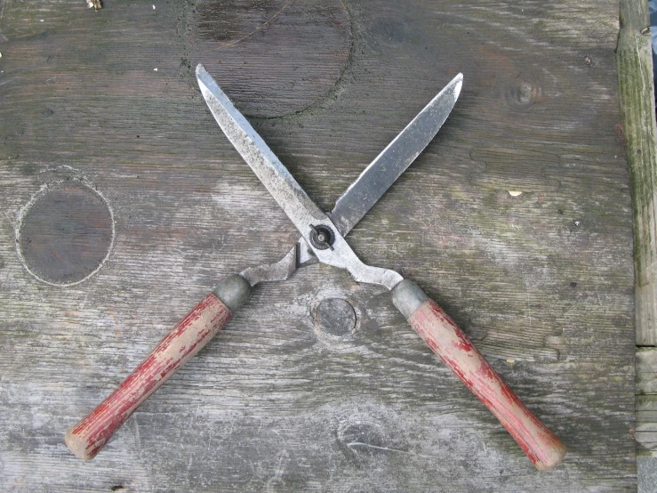 a pair of scissors are crossed on top of a piece of wood