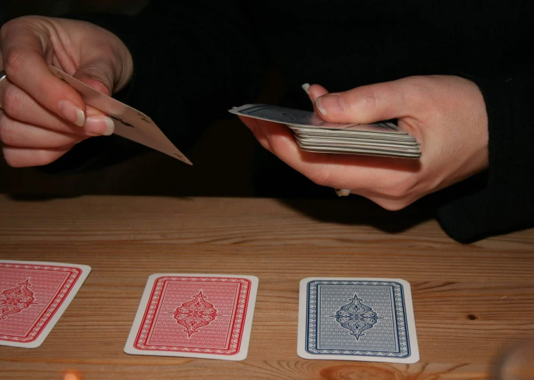 a person is holding scissors above playing cards
