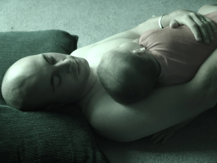 a man in a red shirt holds his sleeping baby