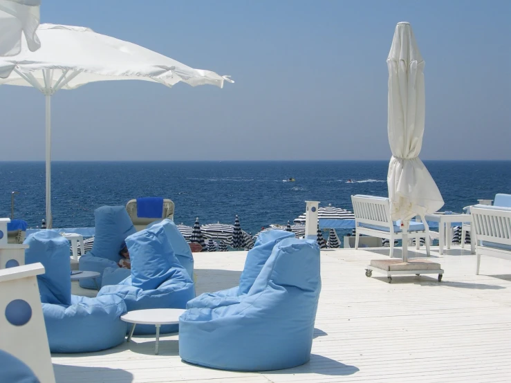 blue lounge chairs and umbrellas on top of a roof over the ocean