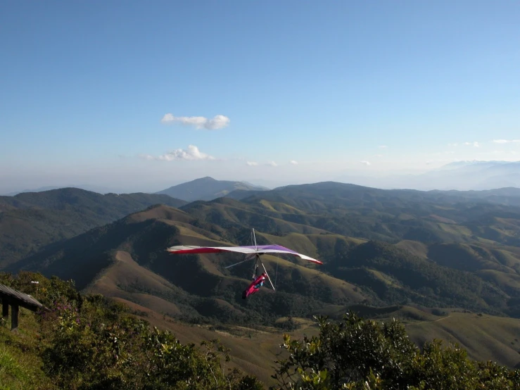 some sort of glider that is in the air above the hills