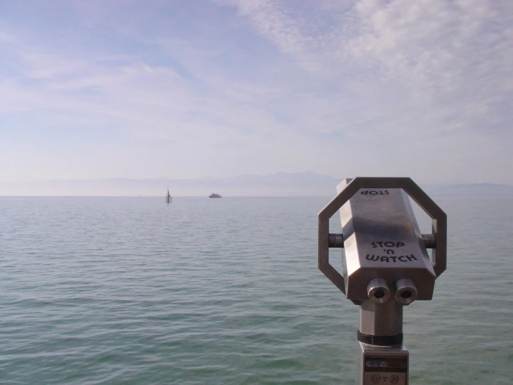 a pole on the water pointing to a boat on the horizon