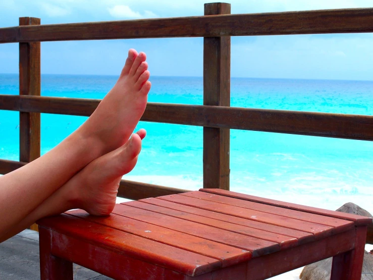 feet resting on a red table looking out at the ocean