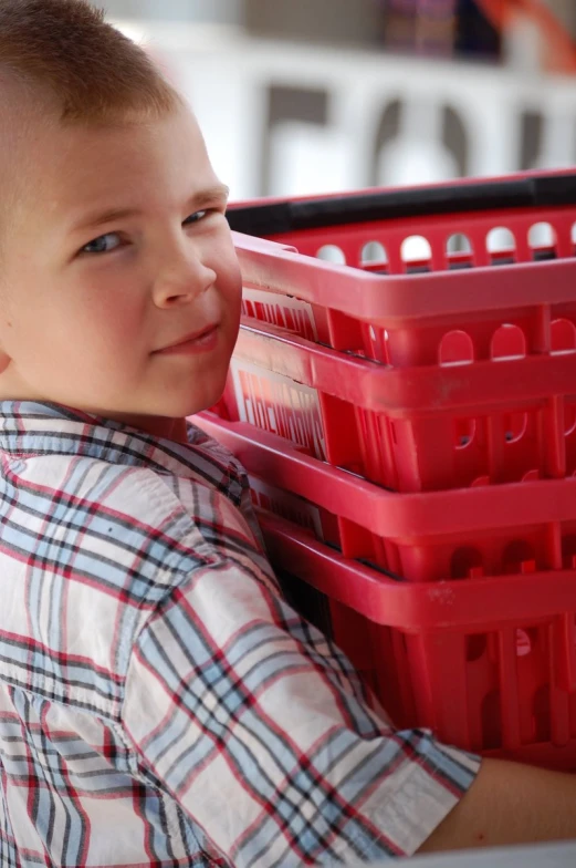 the little boy is holding the small red basket