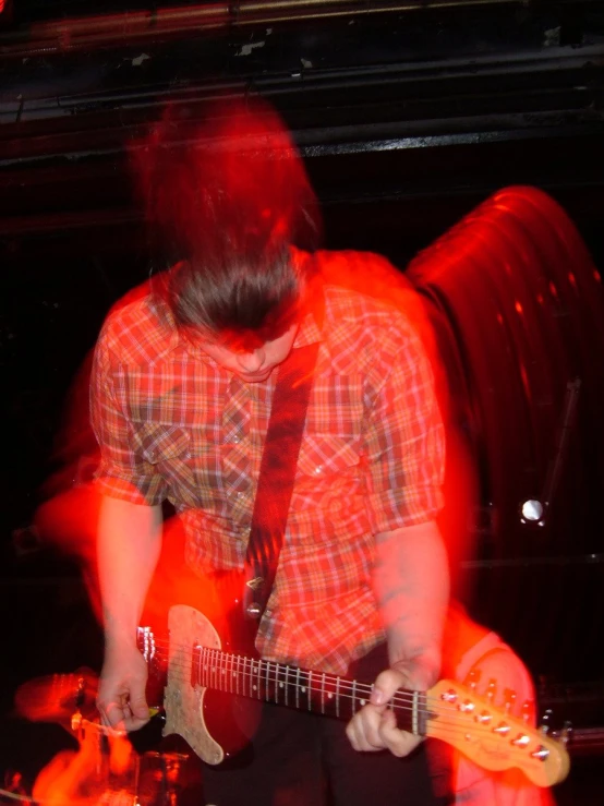 a person playing on a guitar and red lights
