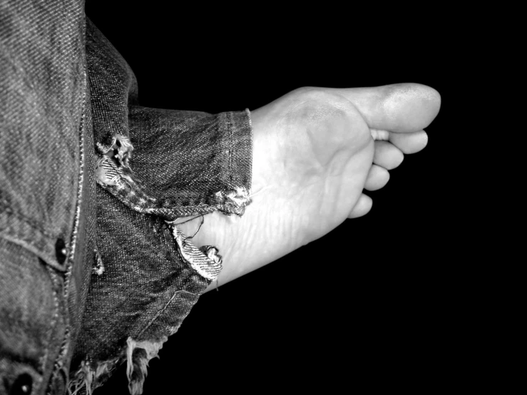 a black and white pograph of someones left hand on an old pair of jeans